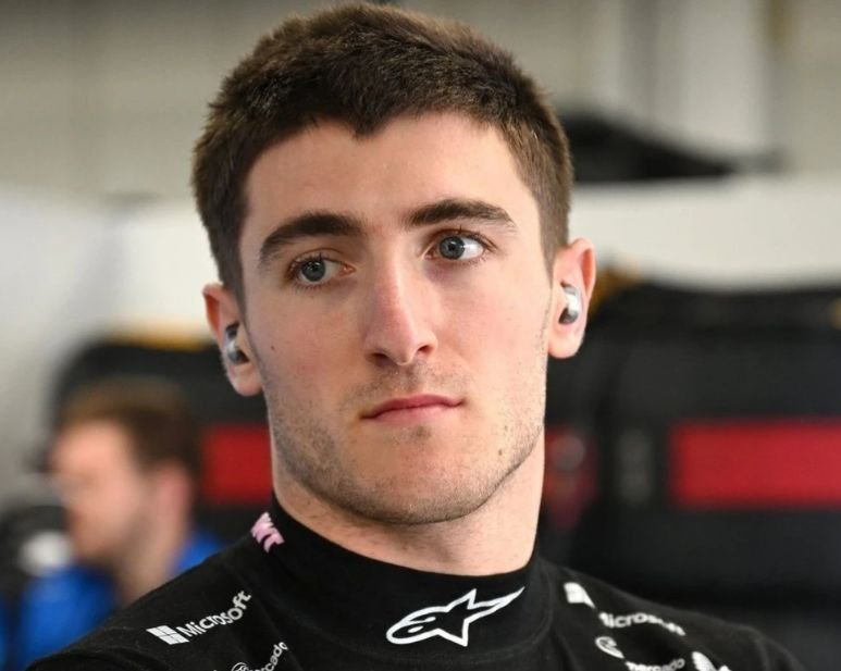 Jack Doohan con su traje de competición en el paddock de Fórmula 2, antes de una jornada de clasificación, mostrando concentración y determinación.